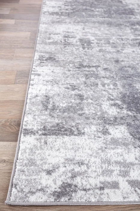 Close-up of the Willington Abstract Ivory/Dark and Light Gray Area Rug on a wooden floor.