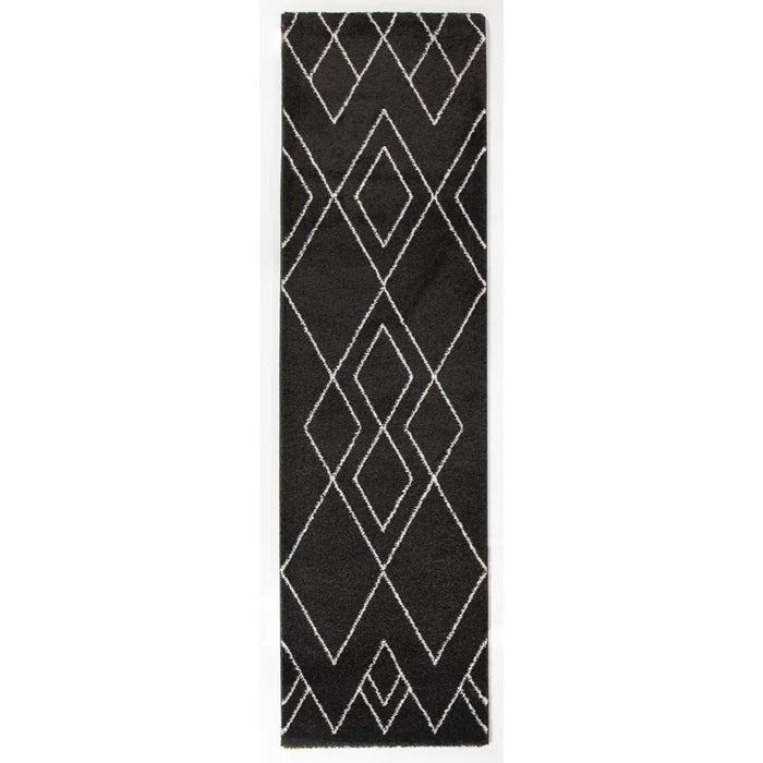 The Dedham Geometric Black Area Rug, featuring a striking white diamond pattern, is set against a white backdrop.