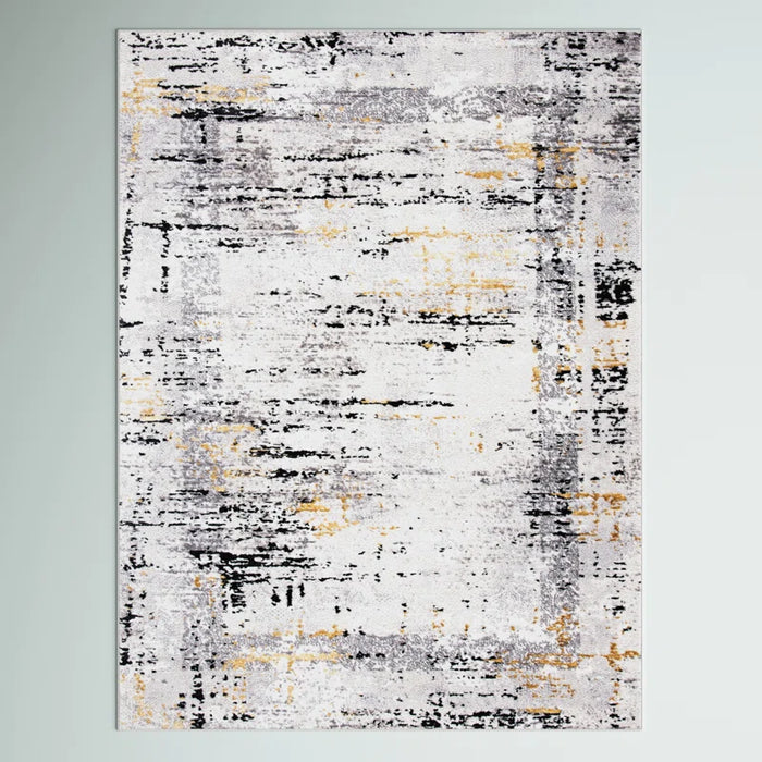 The Acosta Rug is a rectangular area rug showcasing an abstract design with shades of gray, black, and yellow on a light background.