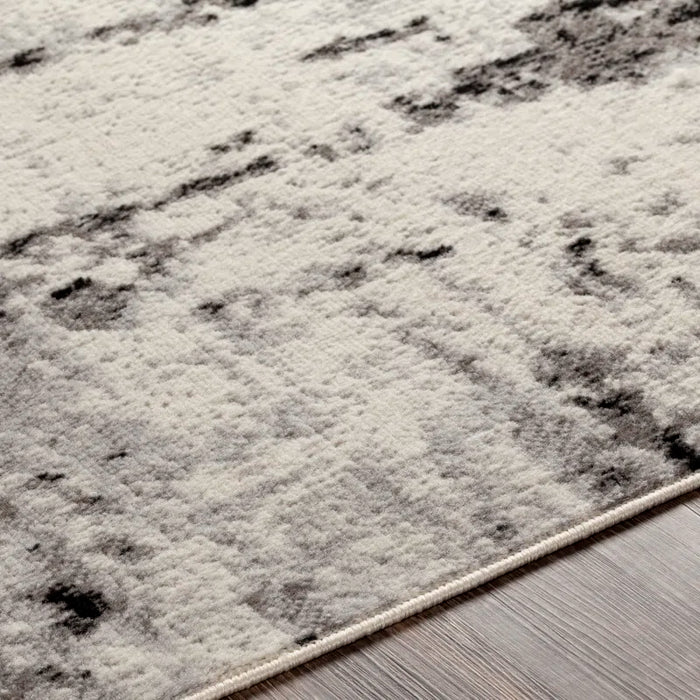 Close-up of the Ceslie Gray/Charcoal Area Rug with a textured design, placed on a wooden floor.