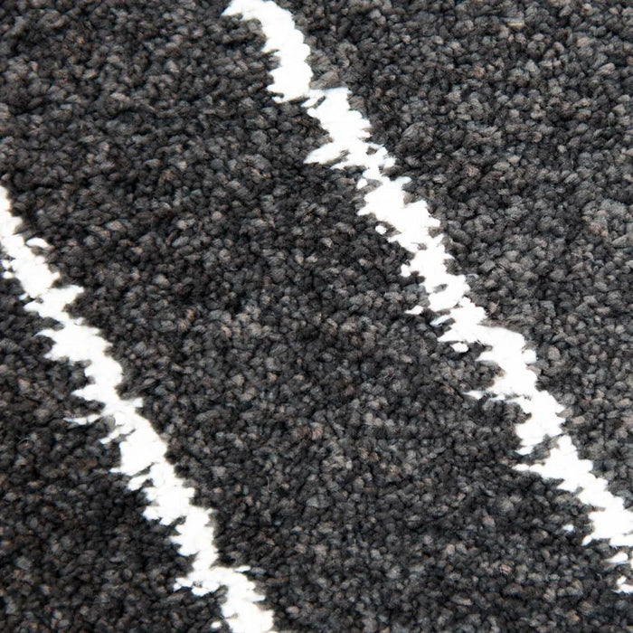 Close-up of the Dedham Geometric Black Area Rug, showcasing its dark gray, textured surface adorned with two irregular, wavy white lines running diagonally across the rug.