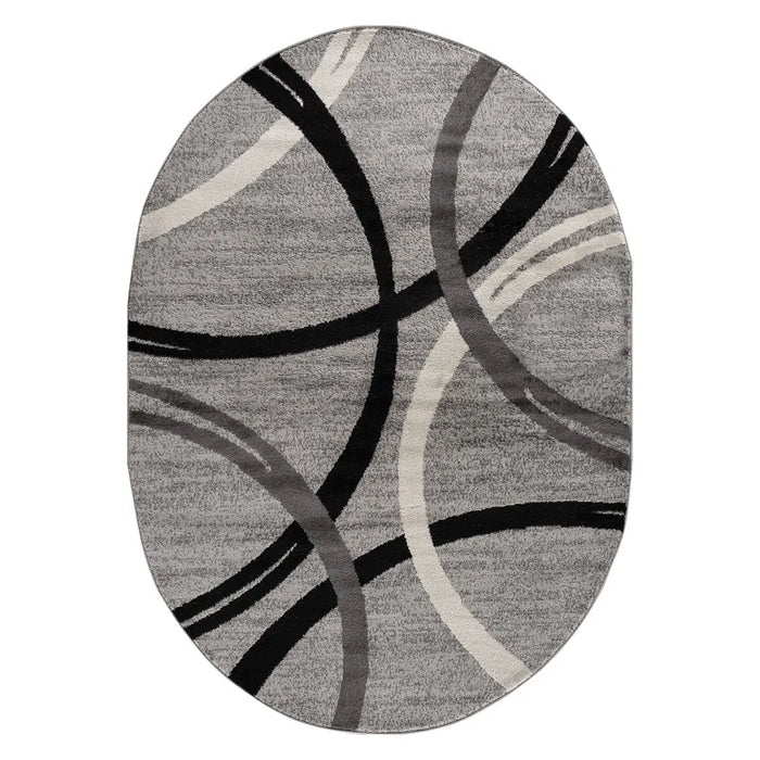 Devonshire Abstract Gray/Black/Ivory Area Rug with a modern oval design featuring overlapping black, ivory, and dark grey curved lines.