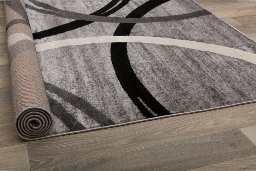 A rolled-up Devonshire Abstract Gray/Black/Ivory Area Rug with abstract curved lines on a wooden floor.