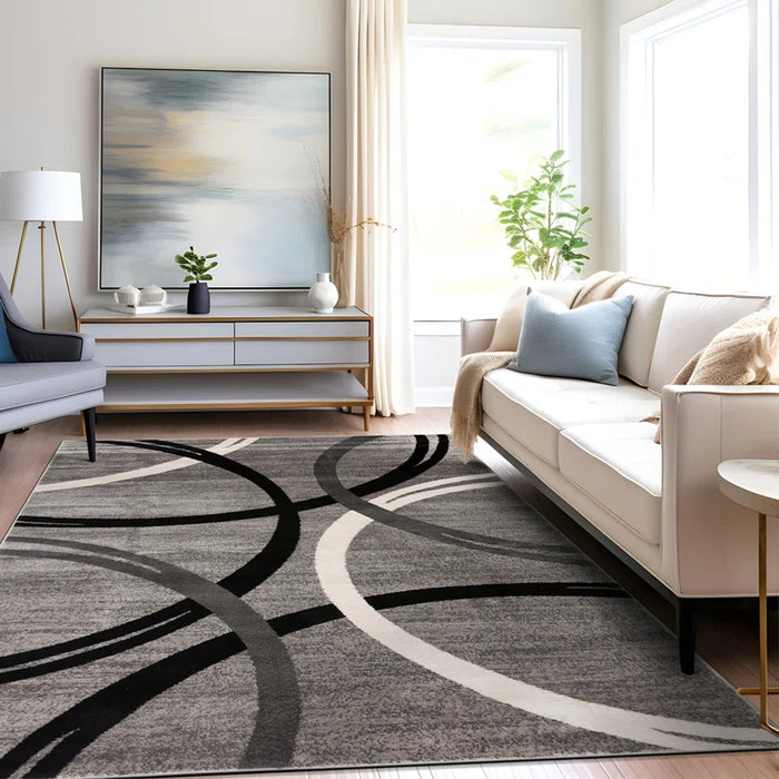 Modern living room with a beige sofa, the Devonshire Abstract Gray/Black/Ivory Area Rug, a large abstract painting, and ample natural light.