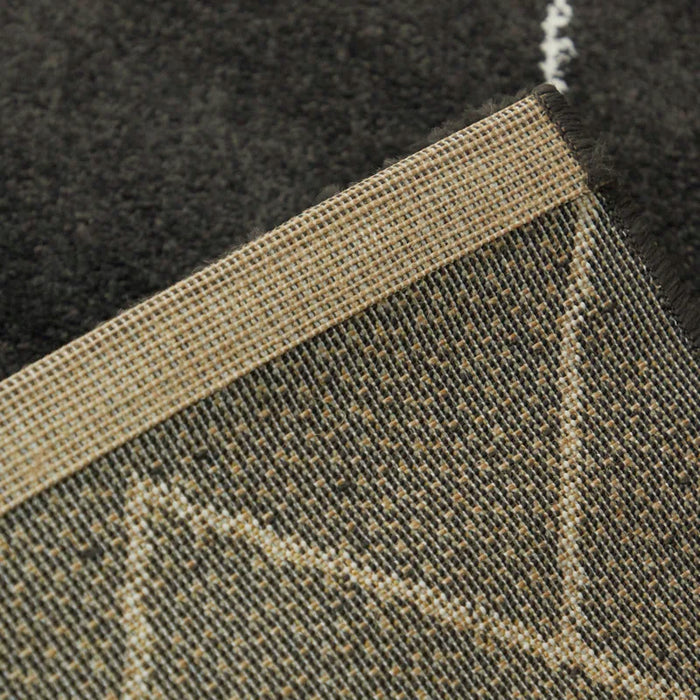 Close-up view of the corner of the folded Dedham Geometric Black Area Rug, showcasing the underside of the rug.