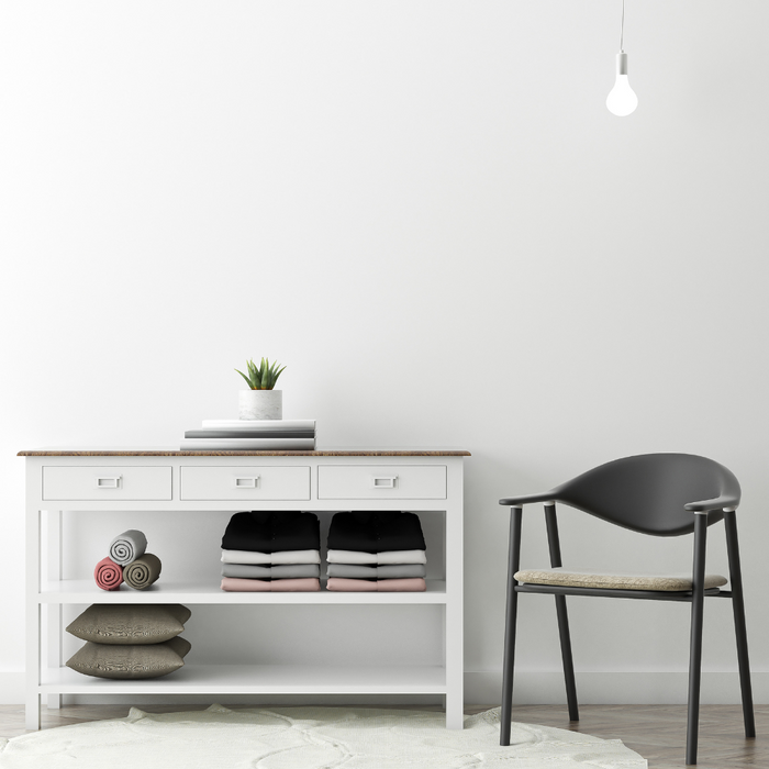 minimalism interior design image containing a black chair next wo a side table with neatly organized towels and pillows on it with a simple plant