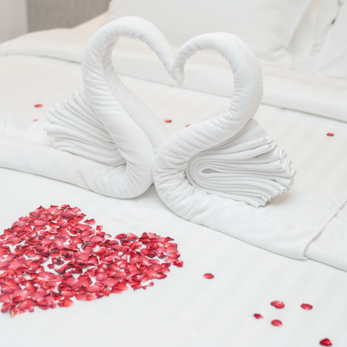 white heart shaped sheets next to a red heart on a bed