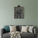 Decorative wall clock on a green wall above a gray sofa with cushions.