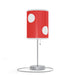 A modern table lamp with a red shade covered in large white dots and a pull chain on a metallic base.