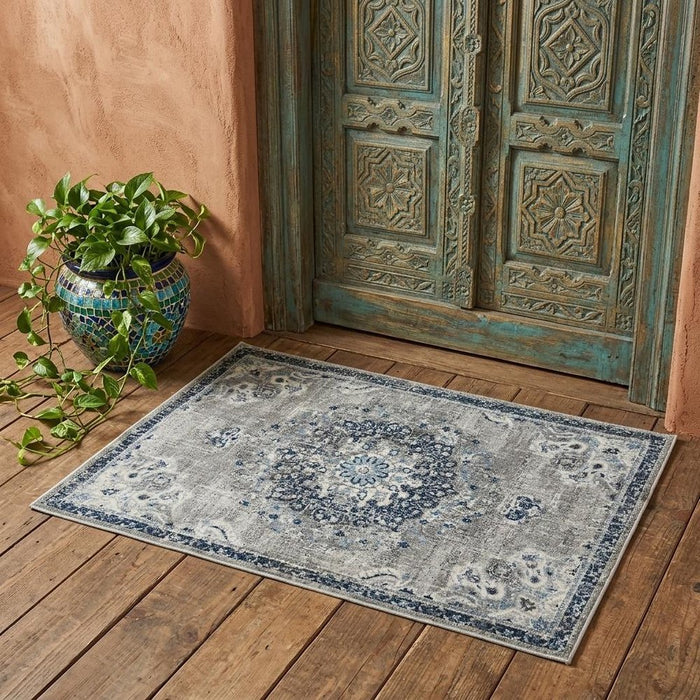 Decorative rug with intricate patterns on a wooden floor next to a textured wall and decorative door.