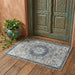 Decorative rug with intricate patterns on a wooden floor next to a textured wall and decorative door.