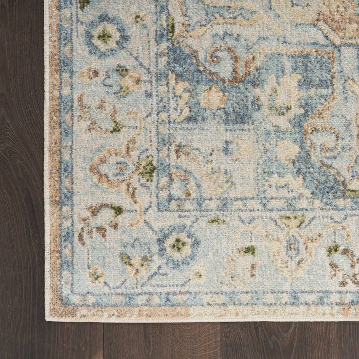 Close-up of a patterned rug with blue and beige colors on a wooden floor.