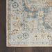 Close-up of a patterned rug with blue and beige colors on a wooden floor.