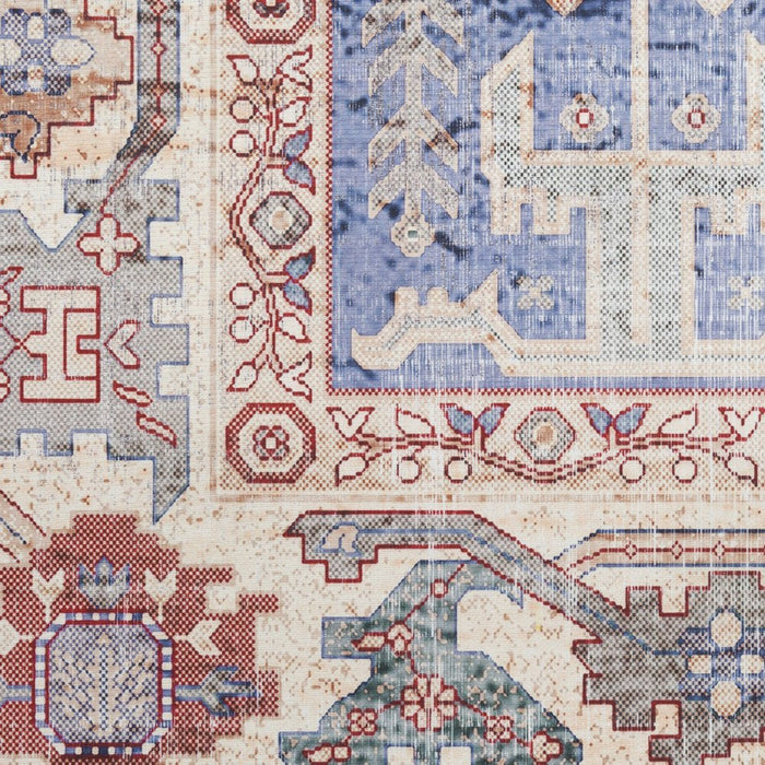 Close-up of a patterned rug with intricate designs in blue, red, and beige.