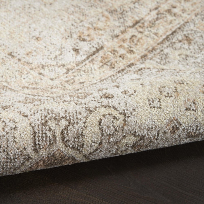 Close-up of a textured beige rug with intricate patterns on a dark surface.