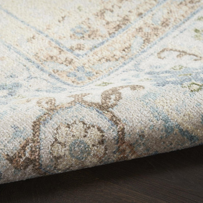 Close-up of a patterned rug with beige, brown, and blue colors on a dark surface.