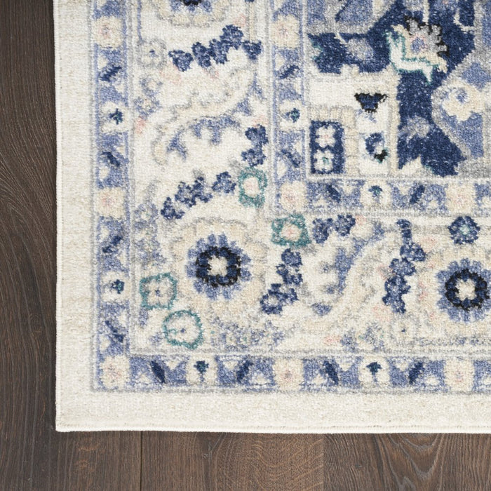 Close-up of a patterned rug with blue and beige colors on a wooden floor.