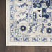 Close-up of a patterned rug with blue and beige colors on a wooden floor.