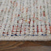 Close-up of a textured multicolored rug on a wooden floor