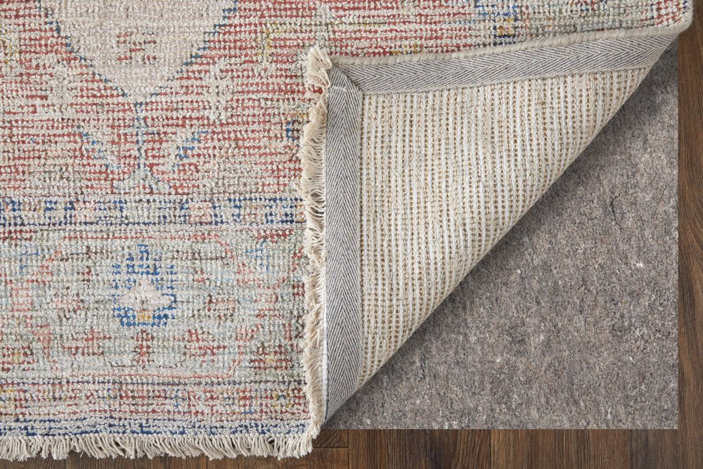 Close-up of a textured rug corner with a gray underlay on a wooden floor.