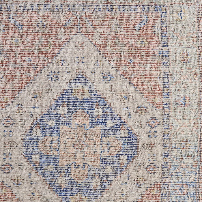 Close-up of a textured rug with a central floral design in blue and beige.
