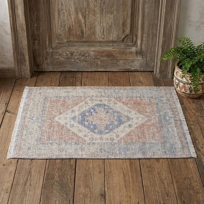 Decorative rug with geometric pattern on a wooden floor next to a wooden door.