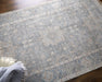 Textured blue rug on a wooden floor with a white shoe and blue towel.