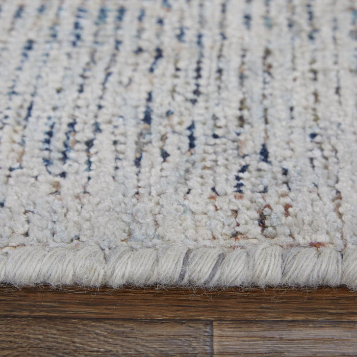 Close-up of a textured rug with a mix of colors on a wooden floor.