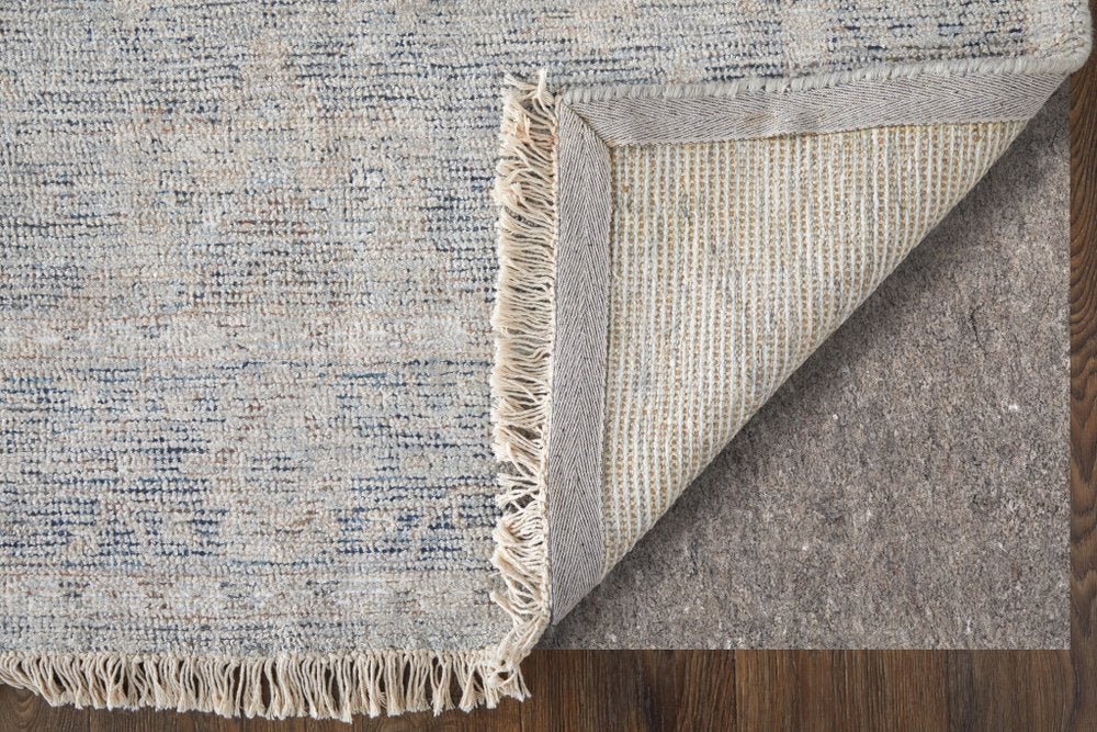 Close-up of a textured rug with fringes on a wooden floor.