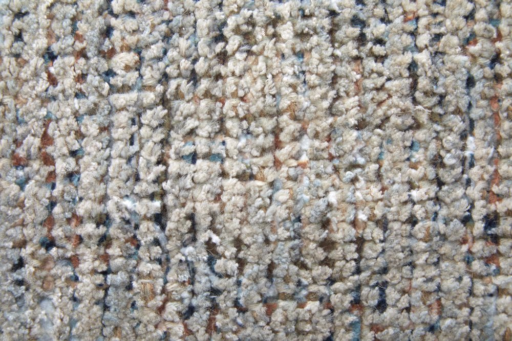Close-up of textured beige carpet with specks of brown and blue