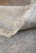 Close-up of textured area rugs with fringe on a wooden floor.