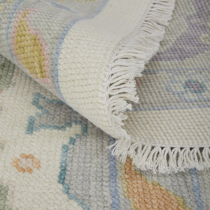 Close-up of a textured rug with floral patterns and white fringe.