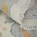 Close-up of a textured rug with floral patterns and white fringe.