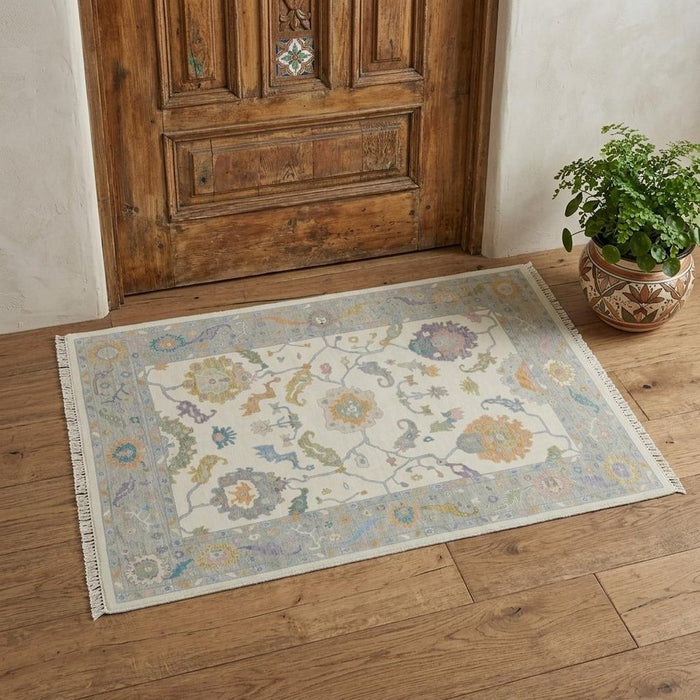Decorative rug with floral patterns on a wooden floor next to a wooden door.