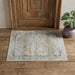 Decorative rug on a wooden floor with a wooden door and plant in the background