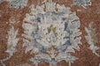 Close-up of a patterned rug with brown, beige, and blue colors.