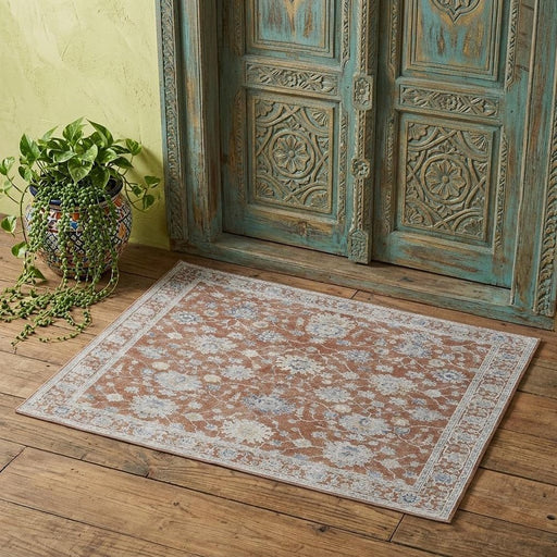 Decorative rug on a wooden floor with an ornate wooden door in the background