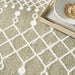Close-up of a textured beige carpet with white geometric patterns, featuring a bowl and tray on top.