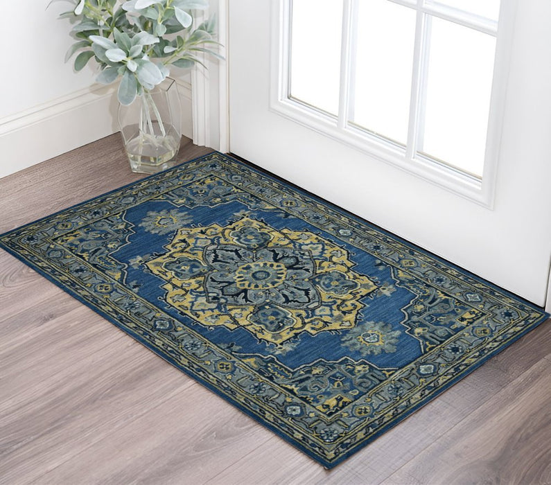 Decorative blue and green rug on a wooden floor with a vase of flowers in the corner.