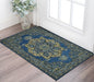 Decorative blue and green rug on a wooden floor with a vase of flowers in the corner.