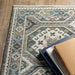 Decorative rug with intricate patterns on a wooden floor, featuring books and a box.