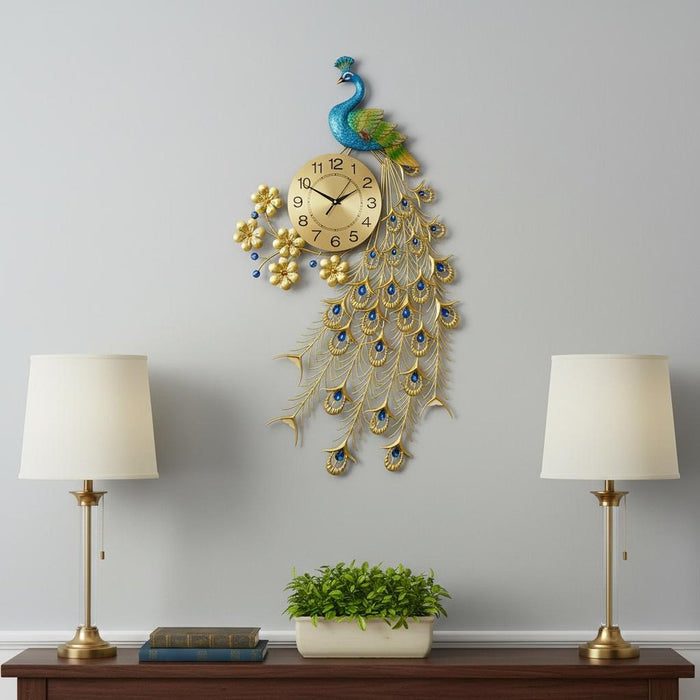 Decorative peacock wall clock on a wall with two lamps and a plant below.