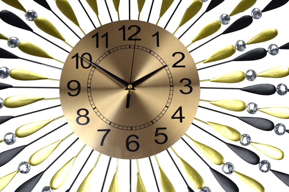 Gold clock with black numbers on a decorative background with yellow and black shapes