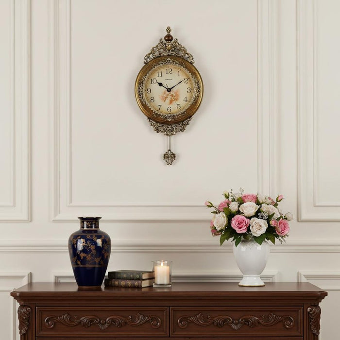 Decorative clock on a wall above a wooden console table with a vase, books, and a candle.