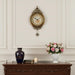 Decorative clock on a wall above a wooden console table with a vase, books, and a candle.