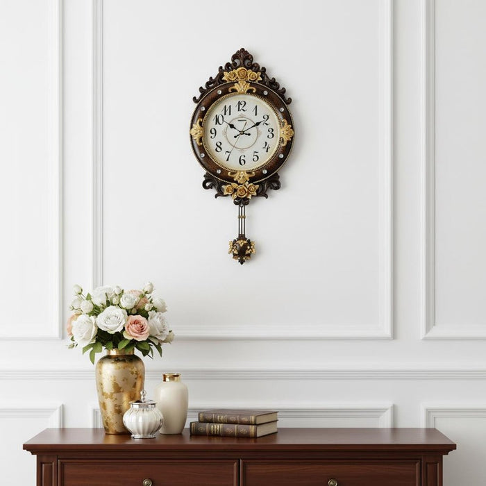 Decorative wall clock with floral design on a white wall above a wooden cabinet with decorative items.
