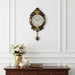 Decorative wall clock with floral design on a white wall above a wooden cabinet with decorative items.