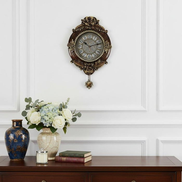 Decorative wall clock above a wooden console table with a vase, books, and flowers.