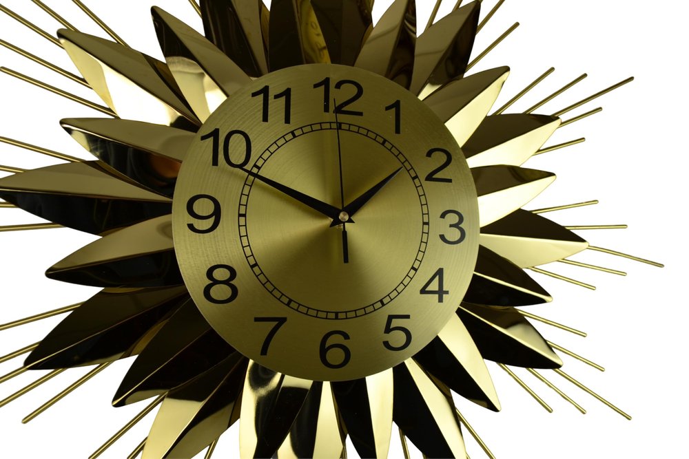 Gold sunburst clock with black numbers on a white background