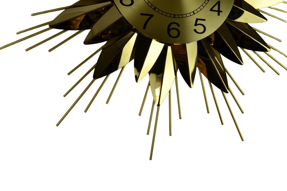 Gold sunburst clock with black numbers on a white background